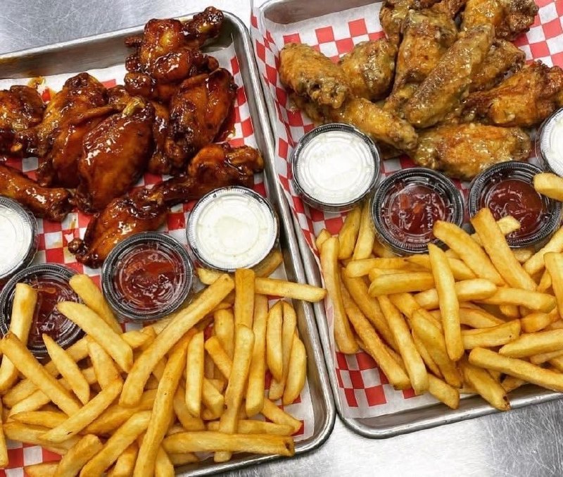Two trays of wings with fries and dipping sauces